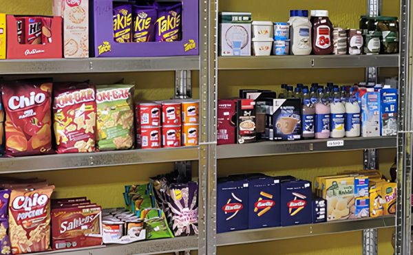 Regale, gefüllt mit verschiedenen Lebensmitteln, darunter Chips, Getränke, Saucen und Snacks.